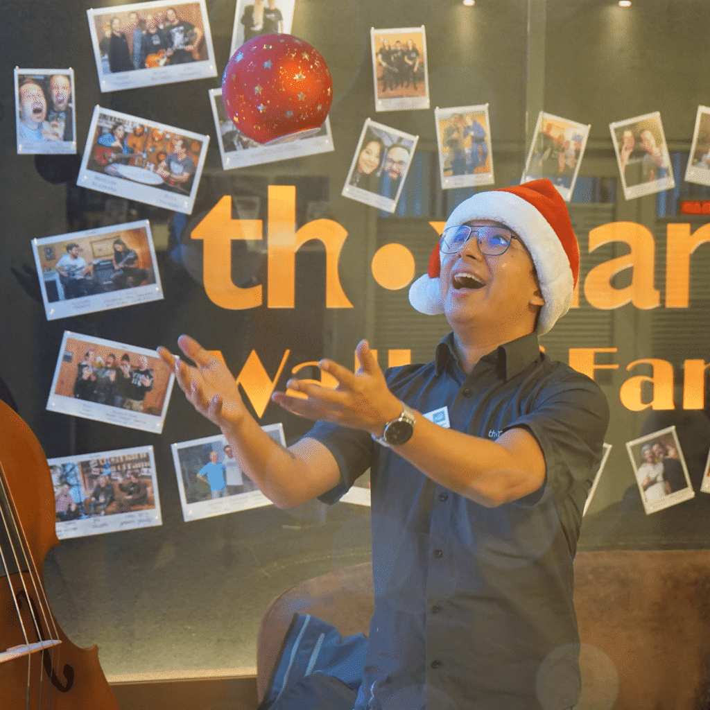 Thomann employee throwing a Christmas ball in the air with an expression of joy.